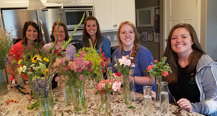 5 happy women arranging flowers in the kitchen